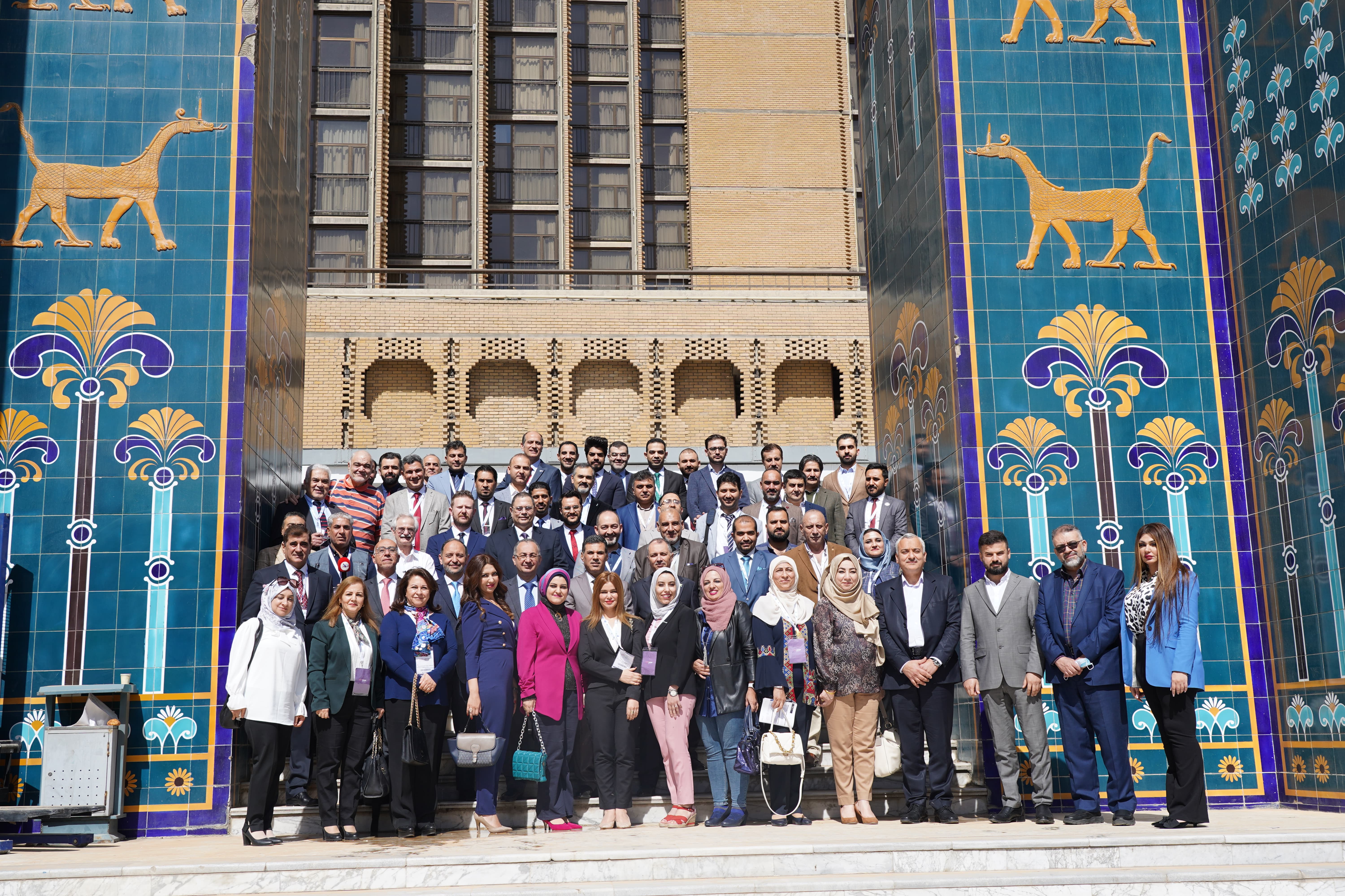 Large group photo of all MOCAT 1 attendees in front of traditional Iraqi architecture